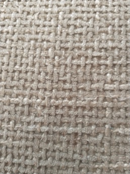 A close-up view of a woven textile fabric showcasing a rough texture with interlaced fibers creating a grid-like pattern.