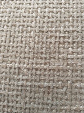 A close-up view of a woven textile fabric showcasing a rough texture with interlaced fibers creating a grid-like pattern.