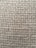 A close-up view of a woven textile fabric showcasing a rough texture with interlaced fibers creating a grid-like pattern.