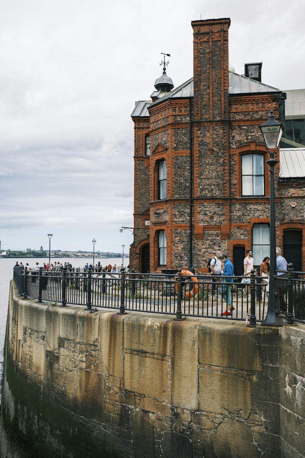 a brick building with a stone wall and a stone wall with people standing on it