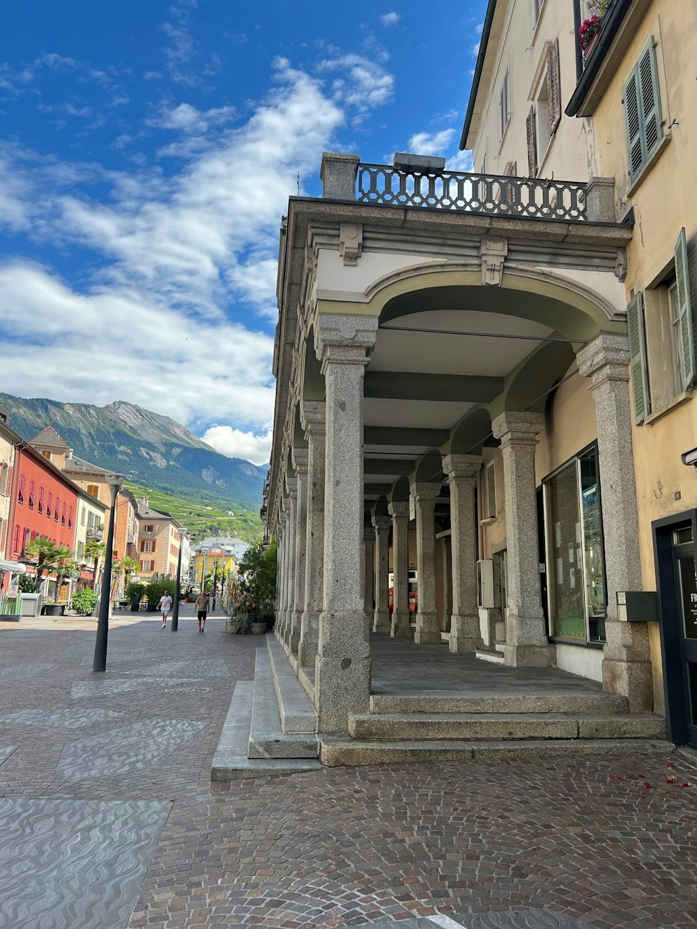 a stone street with buildings and a hill in the background