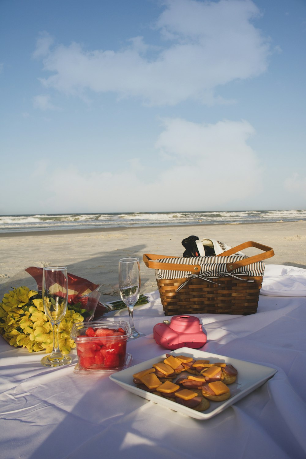 a table with food and glasses on it by a beach