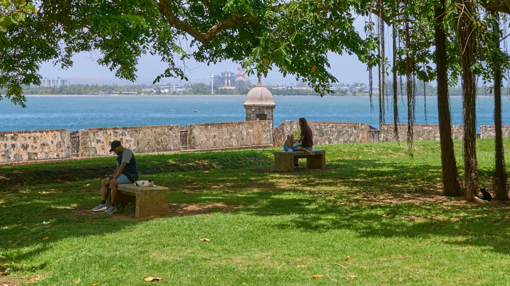 a couple of people sitting on benches by a body of water