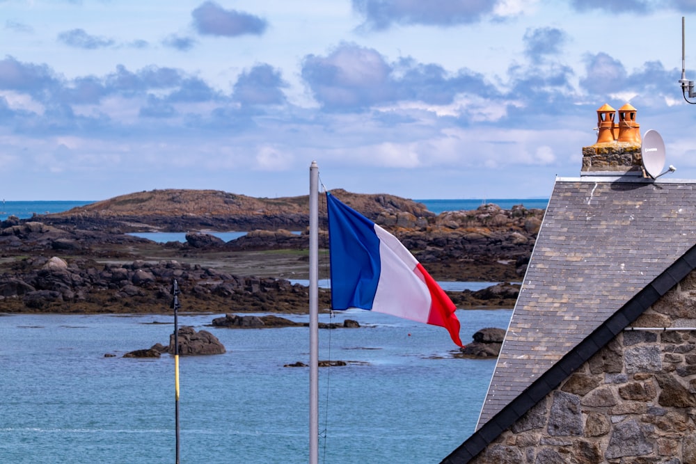 a flag on a pole next to a body of water