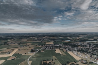 A peaceful rural landscape with patchwork fields and a small farmhouse, seen from the sky.