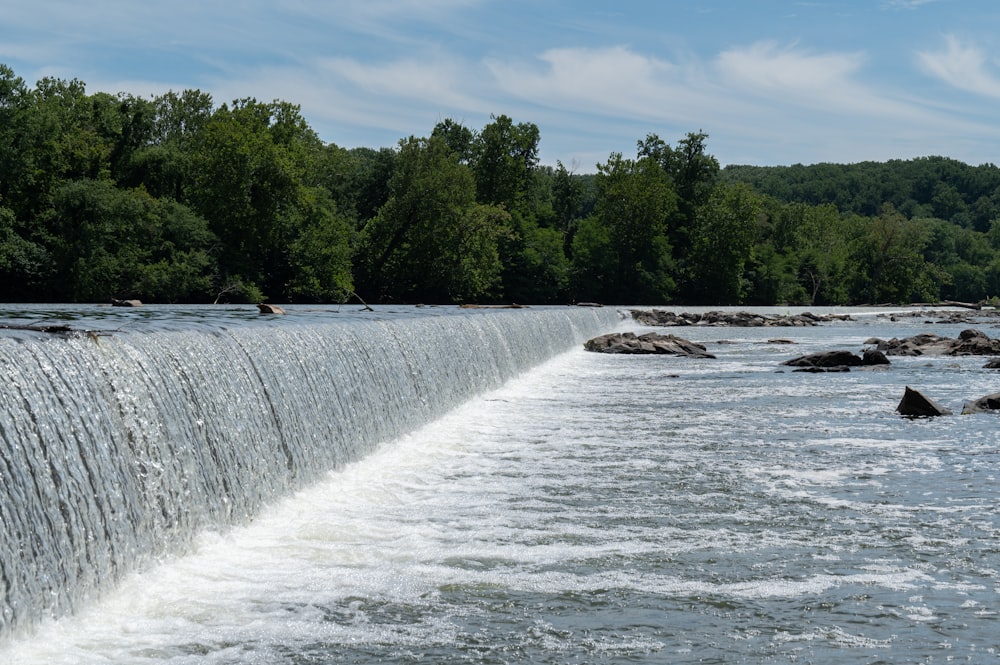 a river with a waterfall and trees