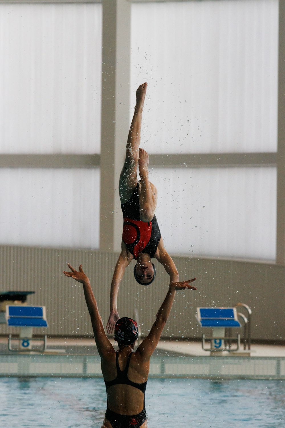 a person holding another man up in the air above a pool