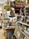 A nostalgic general store displaying a variety of vintage products and advertisements. Shelves are filled with jars of preserves and snacks, and old-fashioned signs such as Coca-Cola and Donald Duck Bread add a retro charm. The store has a cluttered but welcoming atmosphere, with barrels, bags of popcorn, and a colorful assortment of goods.