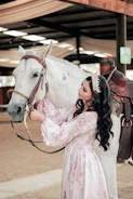 a person in a white dress kissing a horse