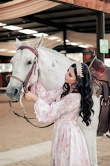 a person in a white dress kissing a horse