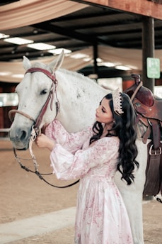 a person in a white dress kissing a horse