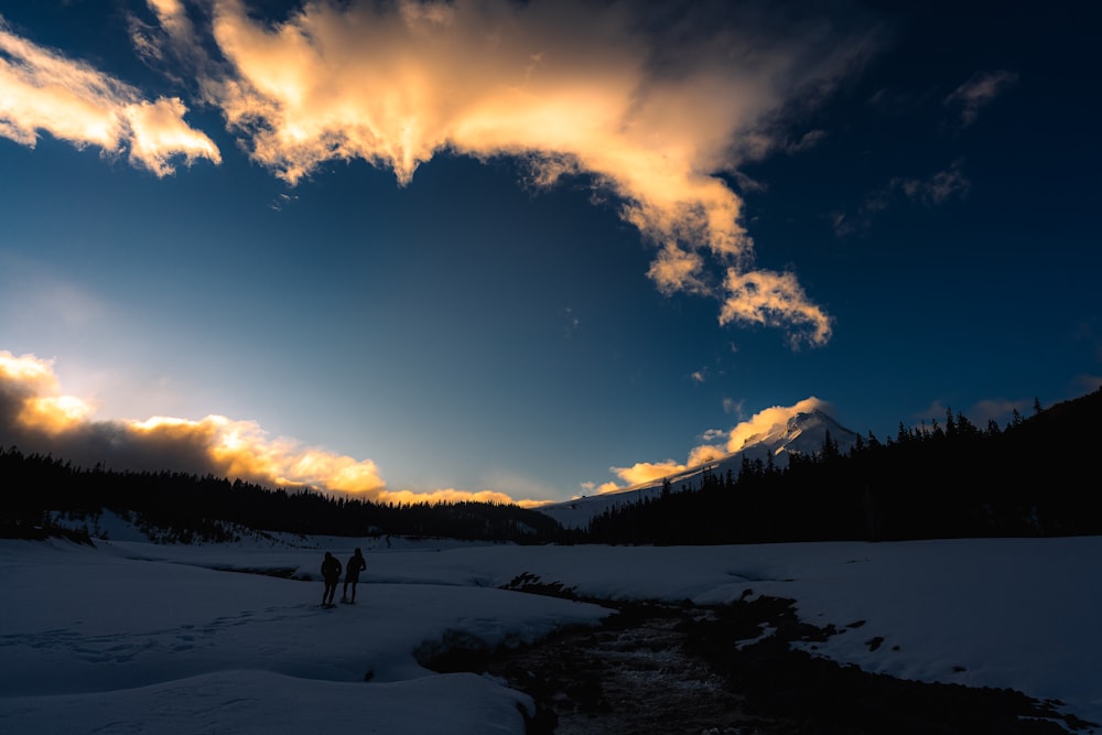 a group of people walking on a snowy road with mountains in the background