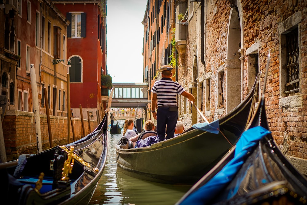 a person and a group of people in a boat on a canal