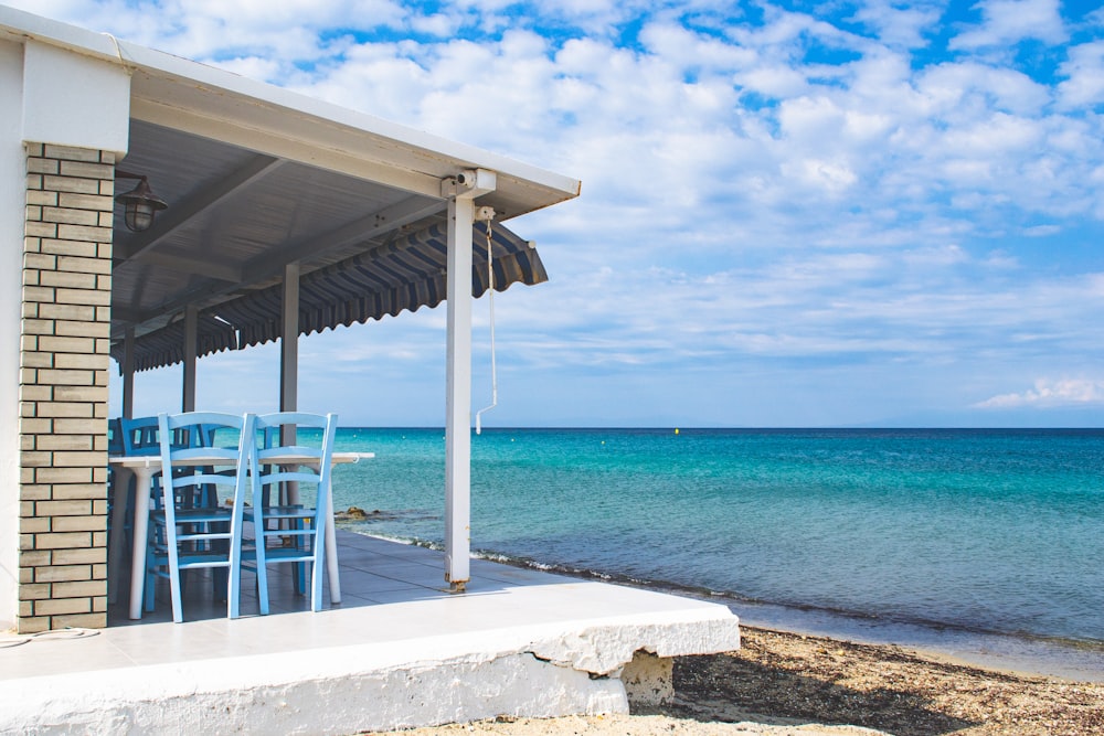 a white building with a white awning and chairs on a beach