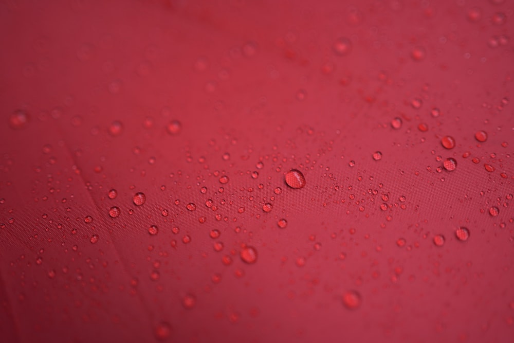 a red surface with water droplets