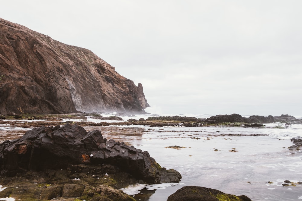 a rocky beach with a large body of water in the background