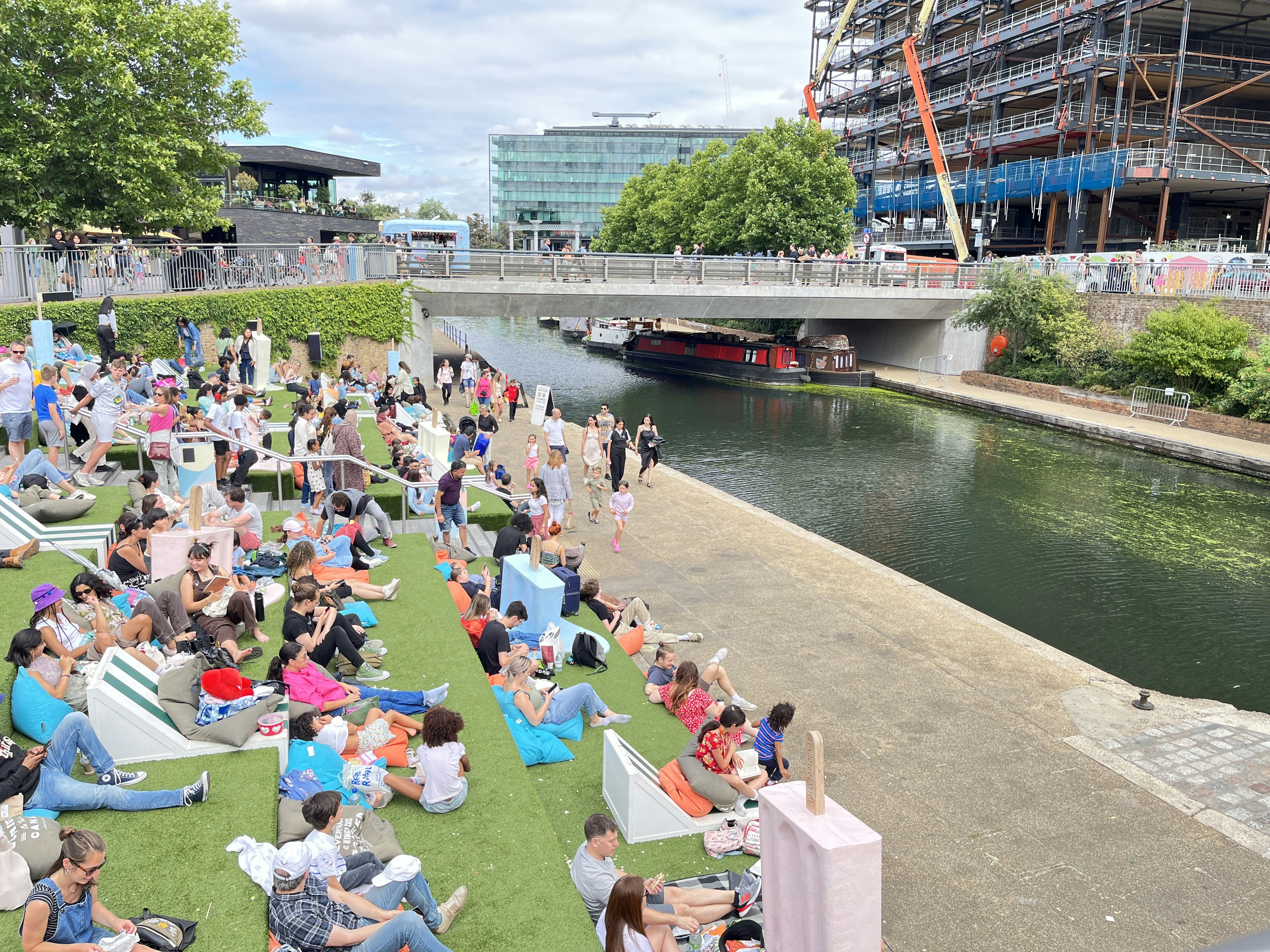 a crowd of people sitting on a dock by a river