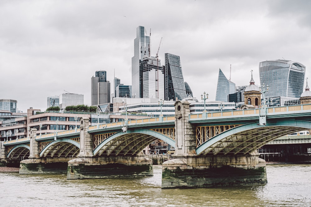 a bridge over a river with a city in the background