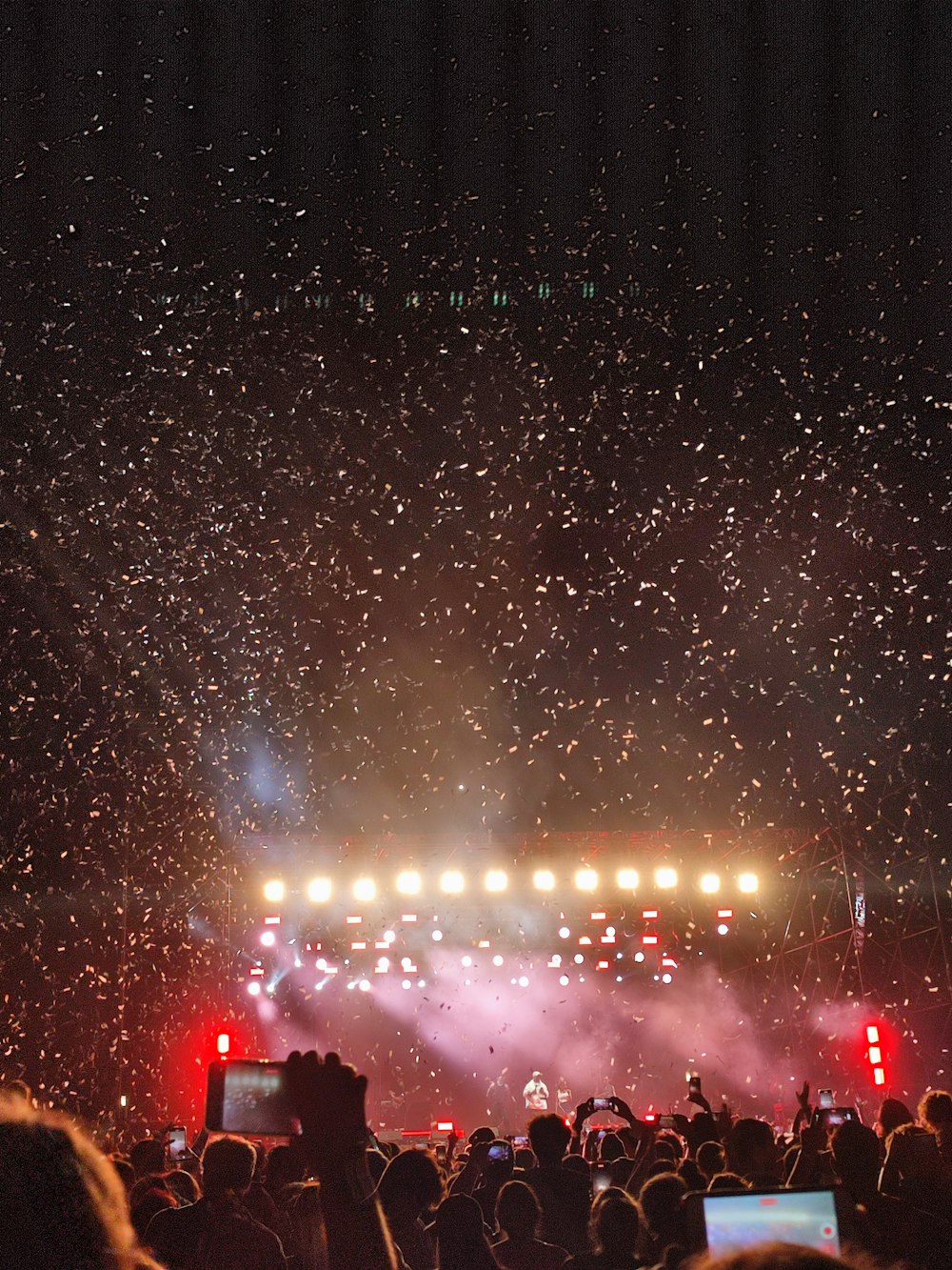 a crowd of people watching a stage with fireworks in the sky