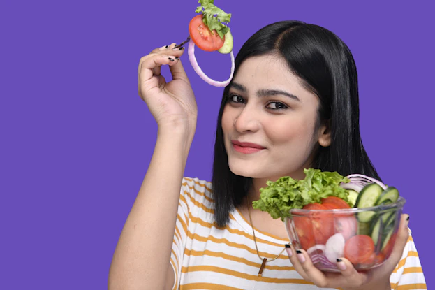 a woman holding a strawberry and a bowl of fruit