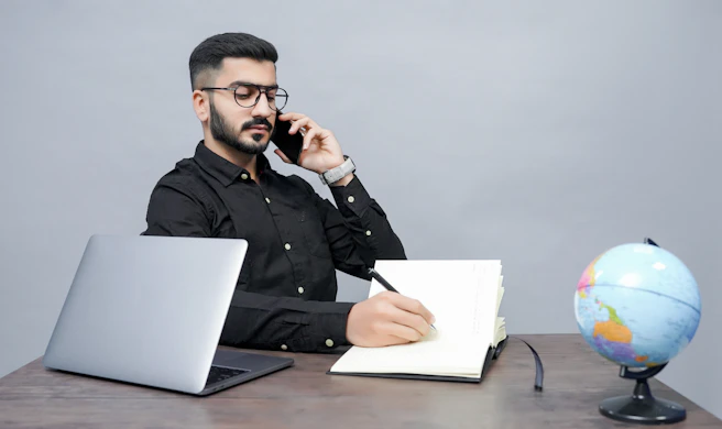 a man holding a pen and a book and a laptop