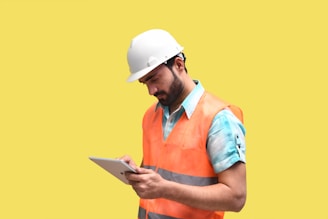 a person wearing a hard hat and looking at a tablet