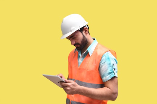 a person wearing a hard hat and looking at a tablet