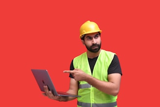 a man wearing a hard hat and holding a laptop