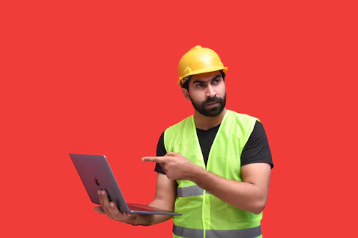 a man wearing a hard hat and holding a laptop