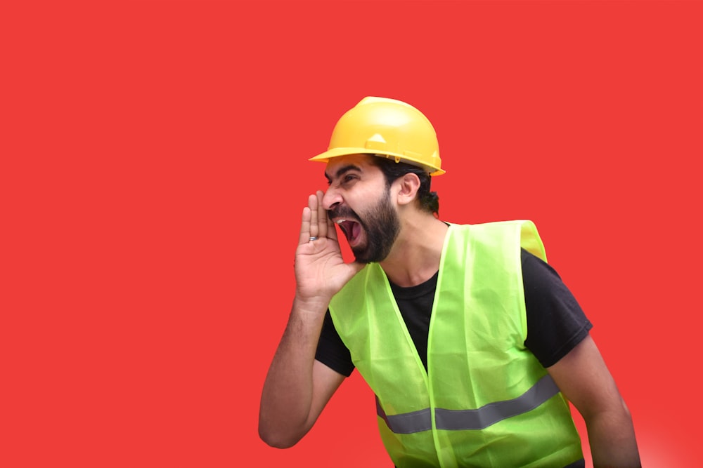 a man wearing a hard hat and holding a phone to his ear