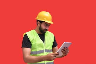 a man in a yellow hard hat holding a tablet
