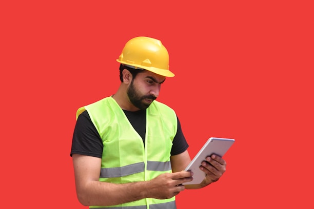 a man in a yellow hard hat holding a tablet