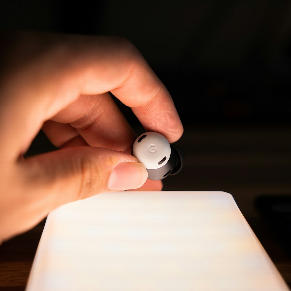 a hand holding a small white object