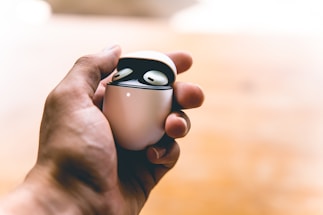 Close-up of hands holding wireless earbuds with charging case.