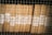 Stacks of organized brown files are secured behind a wire mesh. Each file is labeled with handwritten tags displaying the numbers 1956 and codes like 343 and 352. The scene reflects a methodical storage system, possibly for records or documents.