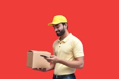 a man in a hard hat holding a phone and a box