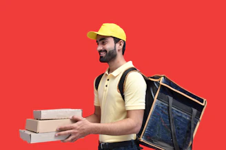 a man in a yellow hat holding a box and a laptop