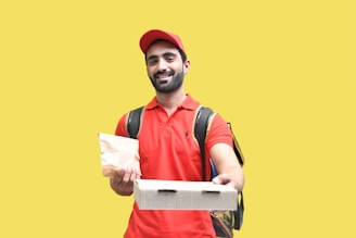 a man in a red vest holding a book and a backpack