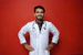 Smiling middle-aged male doctor in a white coat standing confidently in a modern clinic.