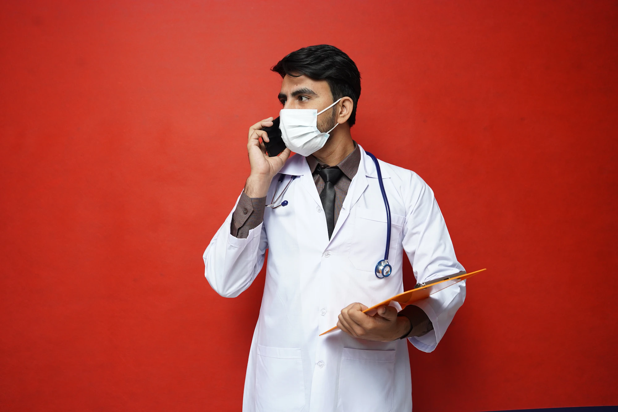 A doctor with a stethoscope checking their phone between consultations