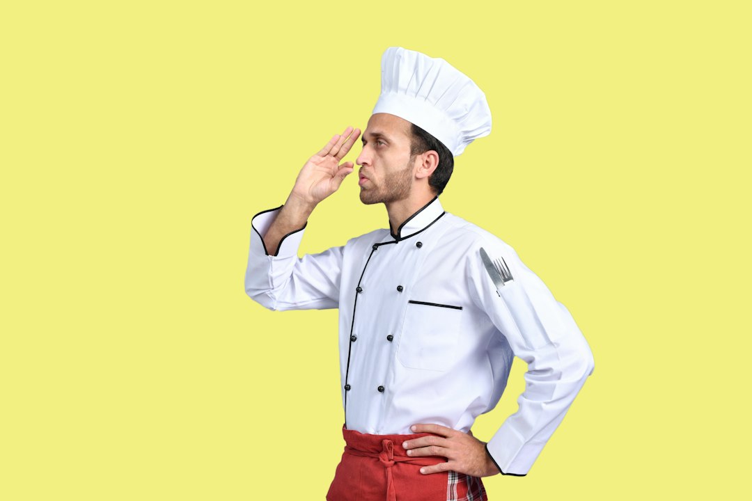 a man in a chef's hat with his hand up