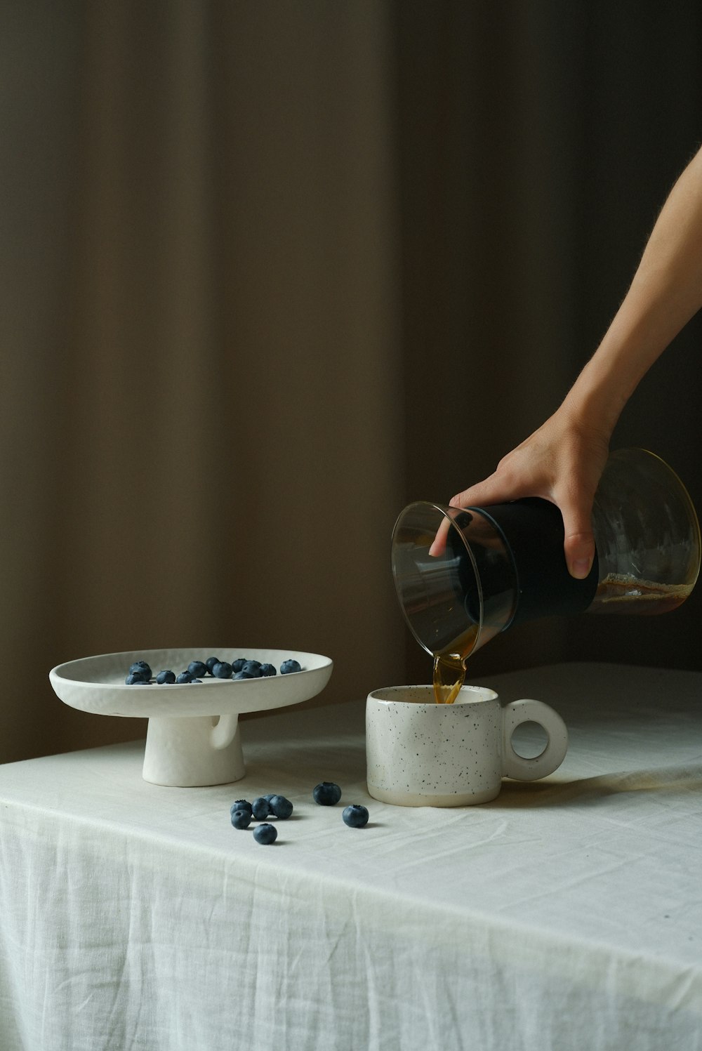 a hand pouring a glass of liquid into a cup