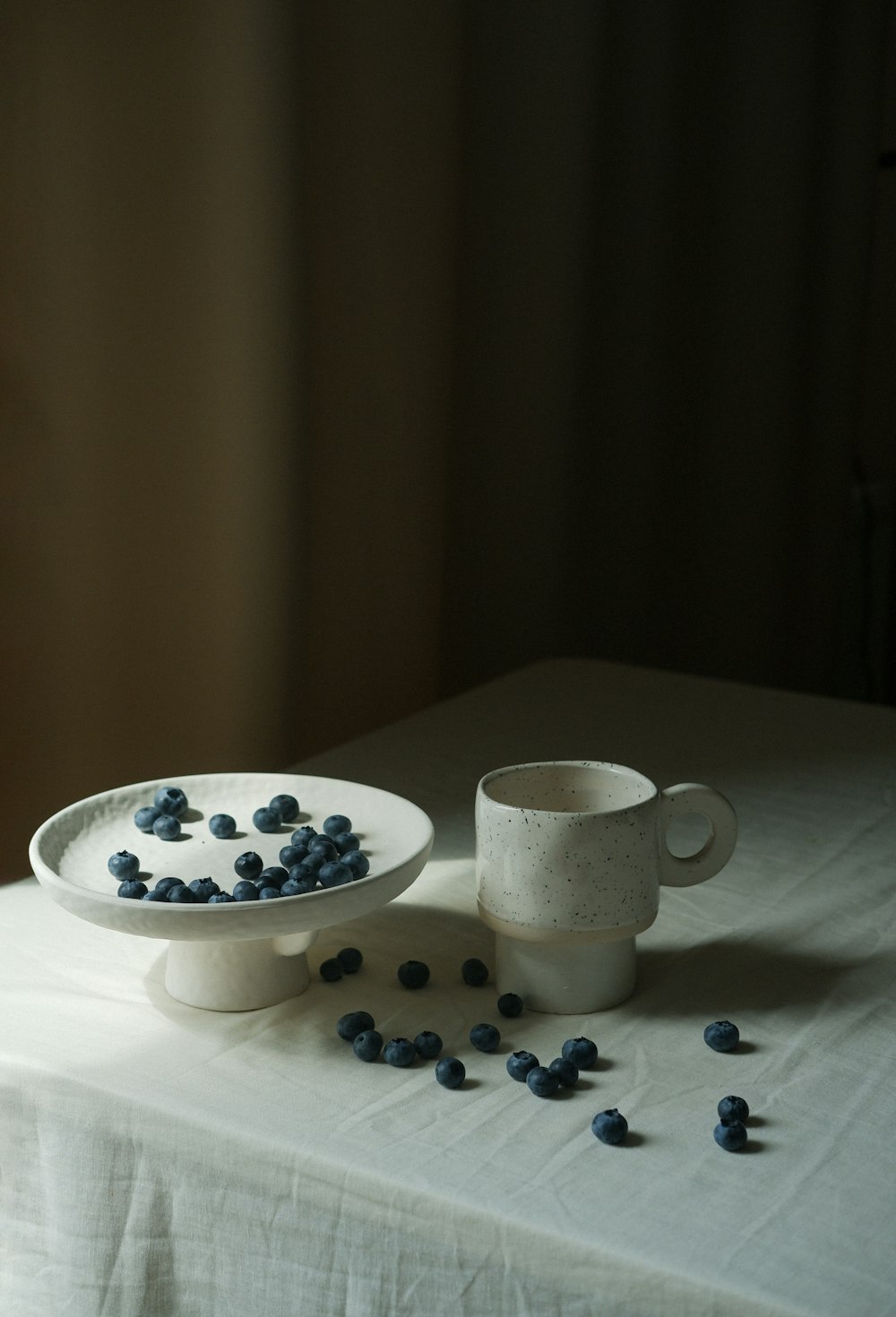 a cup of tea and a bowl of blueberries on a table