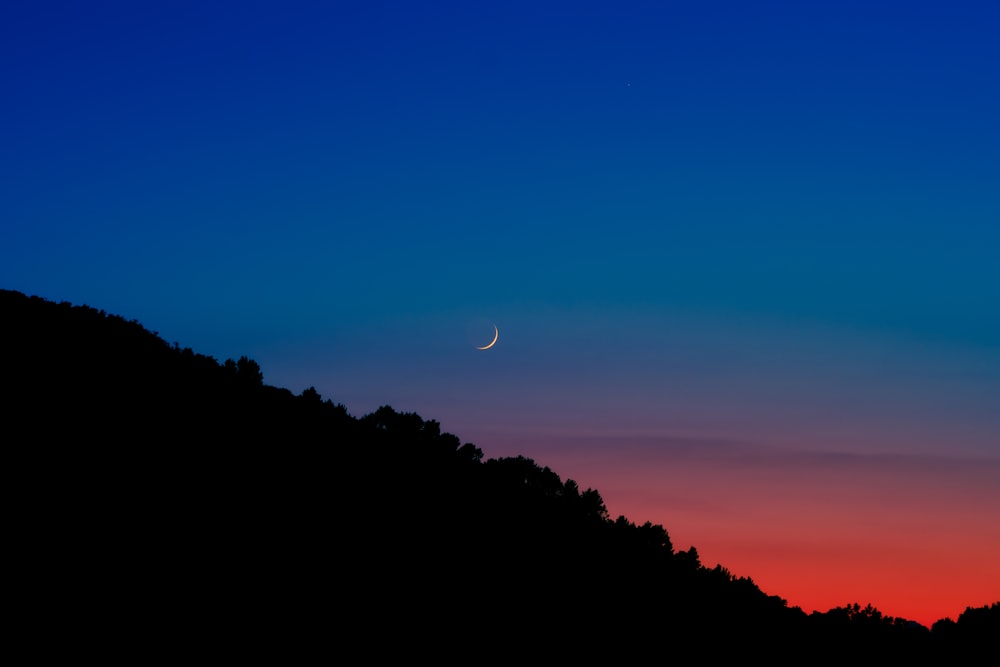 a hill with a moon in the sky