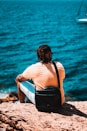 a person sitting on a rock looking at the water