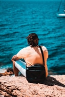 a person sitting on a rock looking at the water