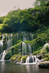 A waterfall cascading down the canyon wall surrounded by vibrant green foliage.