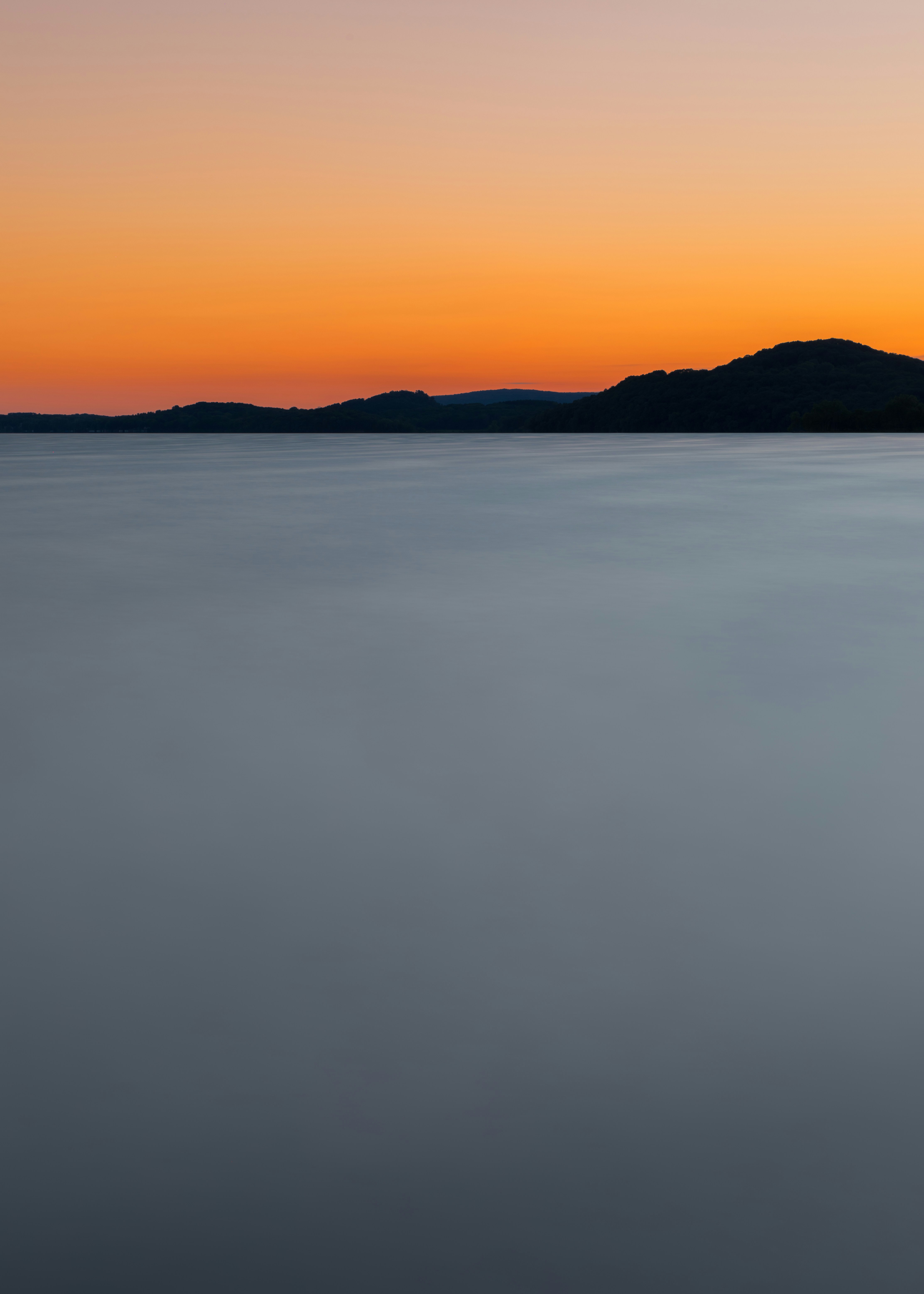 a large body of water with a hill in the background