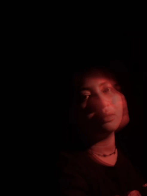 A high-contrast black-and-white portrait with deep red ink bleeding subtly at the edges