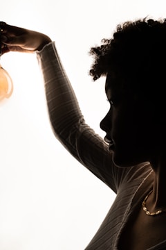 A bright lightbulb glowing above a thoughtful person's head, symbolizing a new idea.